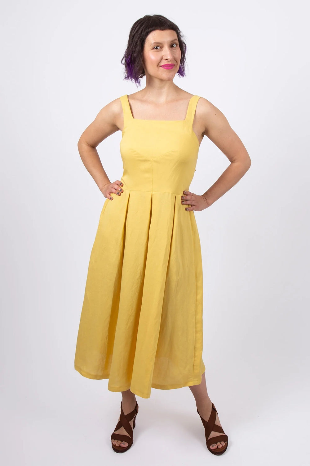Woman wearing the Malorie Dress sewing pattern from Sew Over It on The Fold Line. A dress pattern made in cotton poplin, cotton lawn, viscose, viscose linen or crepe fabric, featuring wide straps, a fitted bodice, pleated skirt, and midi length.
