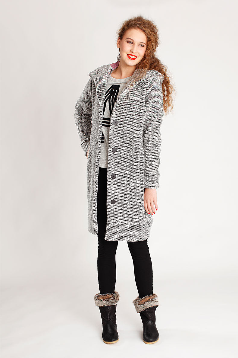 Woman wearing the Malu Coat sewing pattern from Schnittchen Patterns on The Fold Line. A knee-length coat pattern made in wool, denim, or heavyweight cotton fabric, featuring a hood, button front, and lining.