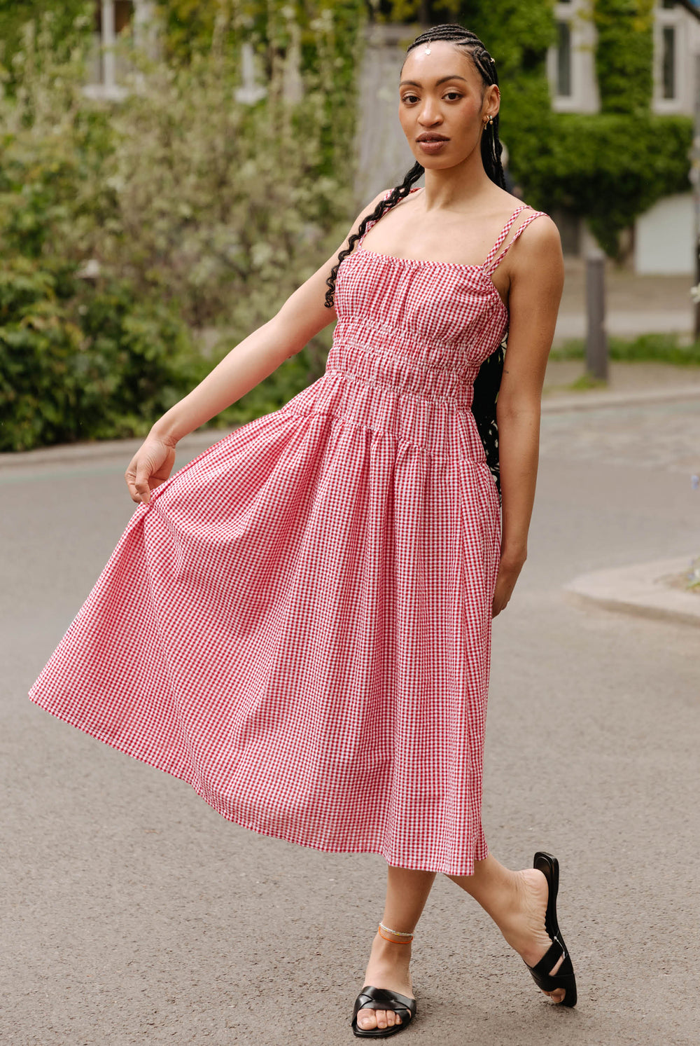 Woman wearing the Margo Dress sewing pattern from JULIANA MARTEJEVS on The Fold Line. A sundress pattern made in cotton fabric, featuring narrow straps, shirring, a gathered skirt, and midi length.