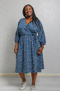 Woman wearing the Margot Dress sewing pattern from Emporia Patterns on The Fold Line. A knit dress pattern made in jersey, lightweight french terry, velour, or ponte roma fabric, featuring a faux wrap bodice, deep V-neck, batwing bracelet-length sleeves, elastic waist, gathered skirt, and in-seam pockets.