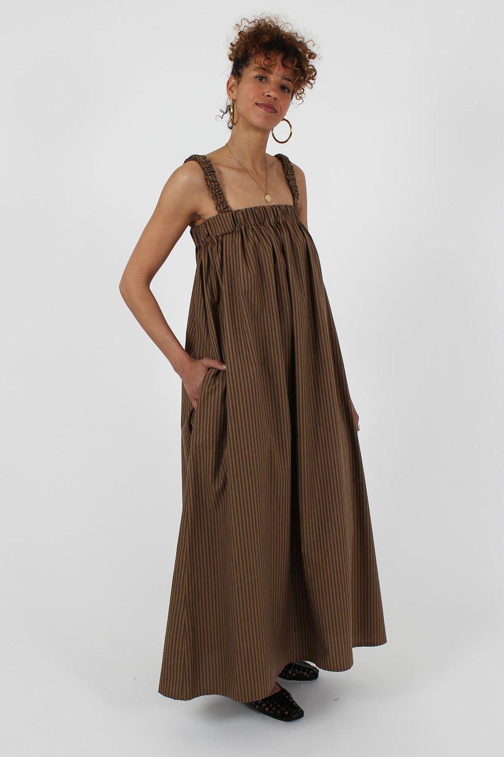Woman wearing the Marguerite Dress sewing pattern from I AM Patterns on The Fold Line. A dress pattern made in silk, viscose, tencel, double gauze, seersucker, lightweight crepe, chambray, satin, linen, or Tana lawn fabric, featuring elasticated straps, pockets, and maxi length.