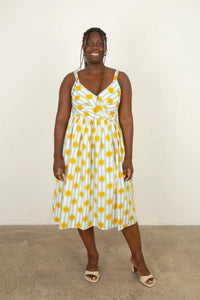 Woman wearing the Maria Dress sewing pattern from Sew Over It on The Fold Line. A sleeveless dress pattern made in cotton lawn, poplin, viscose, or crepe fabric, featuring a V-neckline, bra-friendly straps, faux-wrap pleated bodice, fitted waist, gathered skirt, pockets, and midi length.
