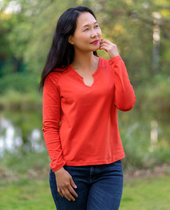 Woman wearing the Mariz Top sewing pattern from Itch to Stitch on The Fold Line. A T-shirt pattern made in knit fabric, featuring a round split neckline, gathers at the shoulders, and long raglan sleeves.