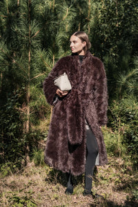 Woman wearing the Marwi Coat sewing pattern from Fibre Mood on The Fold Line. A reversible coat pattern made in faux fur, teddy, or wool fabric, featuring a shawl collar, tie belt, pockets, and calf length.
