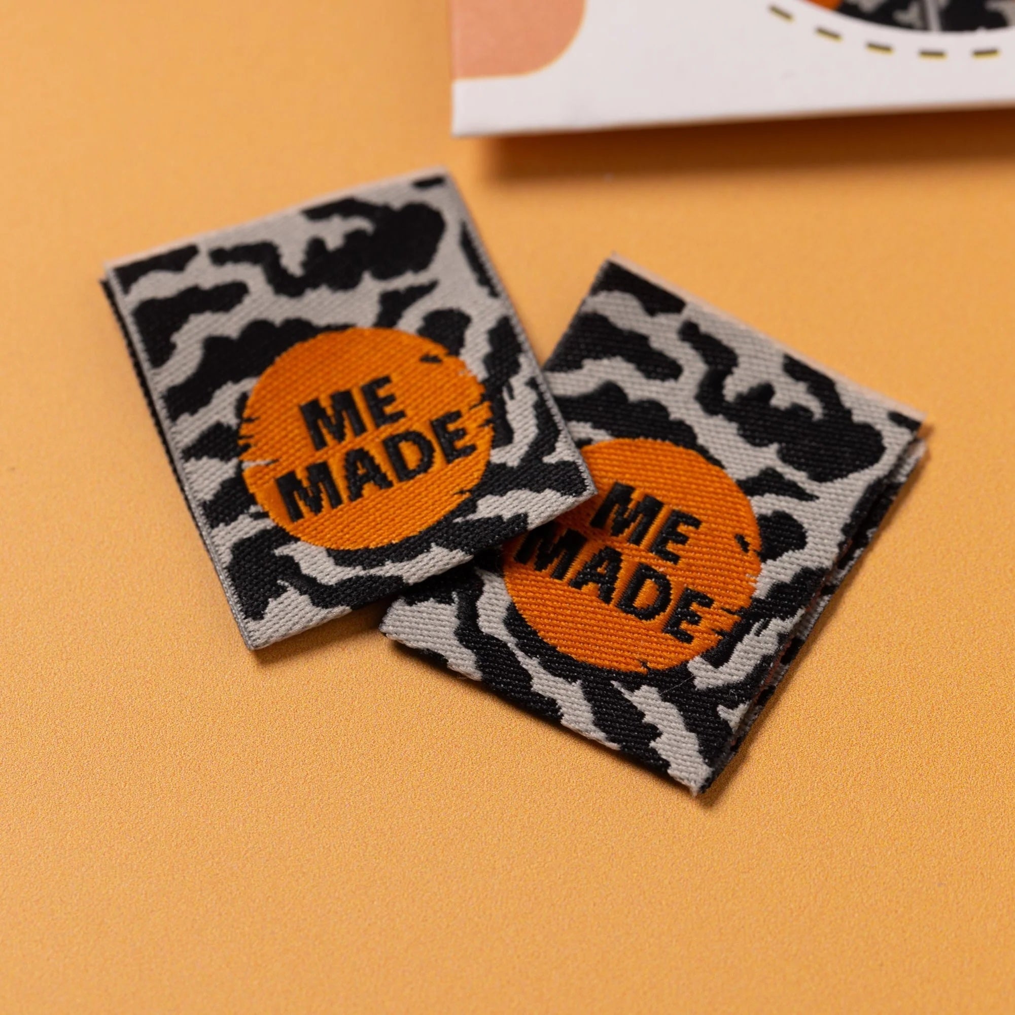 The 'Me Made Zebra' woven labels from Little Rosy Cheeks on The Fold Line. The pack includes 6 labels featuring black text on an orange circle on a zebra print background, ready to be sewn into your handmade clothes.