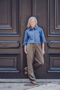 Woman wearing the Melody Shirt sewing pattern from Fibre Mood on The Fold Line. A shirt pattern made in denim, poplin, textured cotton, fine corduroy, woven jacquard, chambray, or satin fabric, featuring a boxy shape, collar, button front, chest pocket, short sleeves, and cropped length.