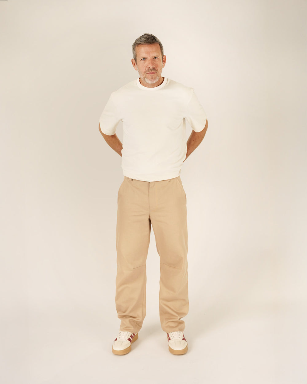 Man wearing the Men's Barrel Chino Pants sewing pattern from Wardrobe by Me on The Fold Line. A trousers pattern made in bottom weight woven cotton, linen, canvas, or denim fabric, featuring a relaxed barrel leg, waistband with belt loops, fly front zipper, side pockets, and back welt pockets.