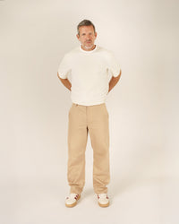 Man wearing the Men's Barrel Chino Pants sewing pattern from Wardrobe by Me on The Fold Line. A trousers pattern made in bottom weight woven cotton, linen, canvas, or denim fabric, featuring a relaxed barrel leg, waistband with belt loops, fly front zipper, side pockets, and back welt pockets.