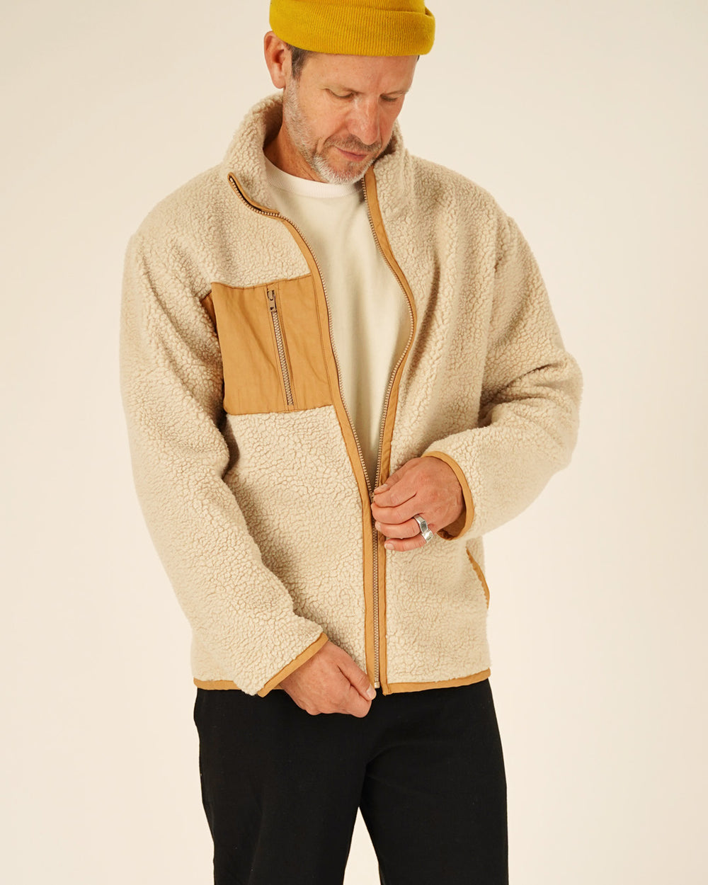Man wearing the Men's Cozy Fleece Jacket sewing pattern from Wardrobe by Me on The Fold Line. A jacket pattern made in teddy fleece, polar fleece, or quilted fabric, featuring a high collar, zip front, contrast chest panel with a zip pocket, and in-seam welt pockets.