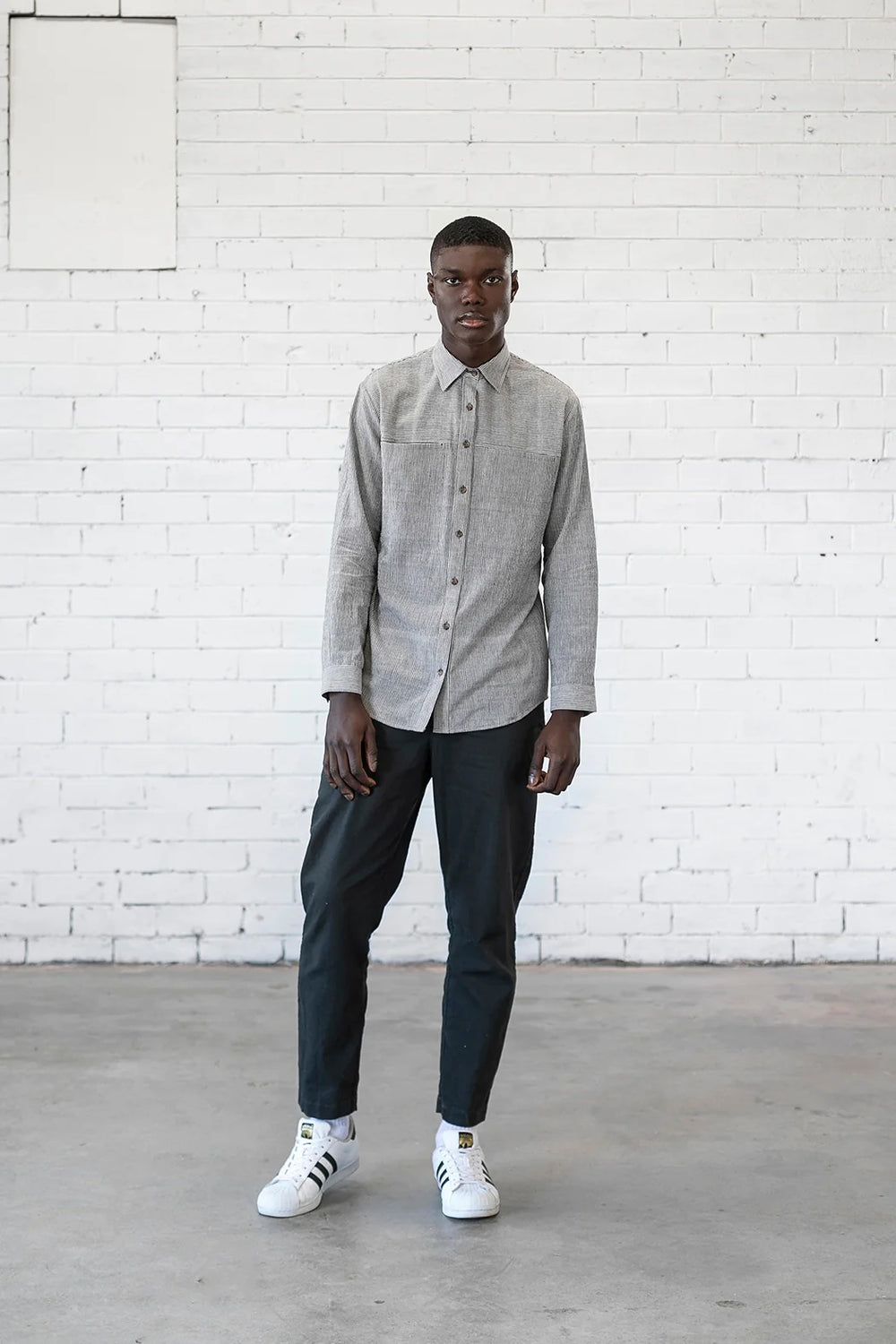 Man wearing the Men's Sanders Button Up sewing pattern from Elbe Textiles on The Fold Line. A shirt pattern made in soft cotton shirting, washed linen, woven hemp blends, lightweight denim, or flannelette fabric, featuring a semi-fitted shape, collar, front yoke with in-seam pockets, button front, and long sleeves with cuffs.