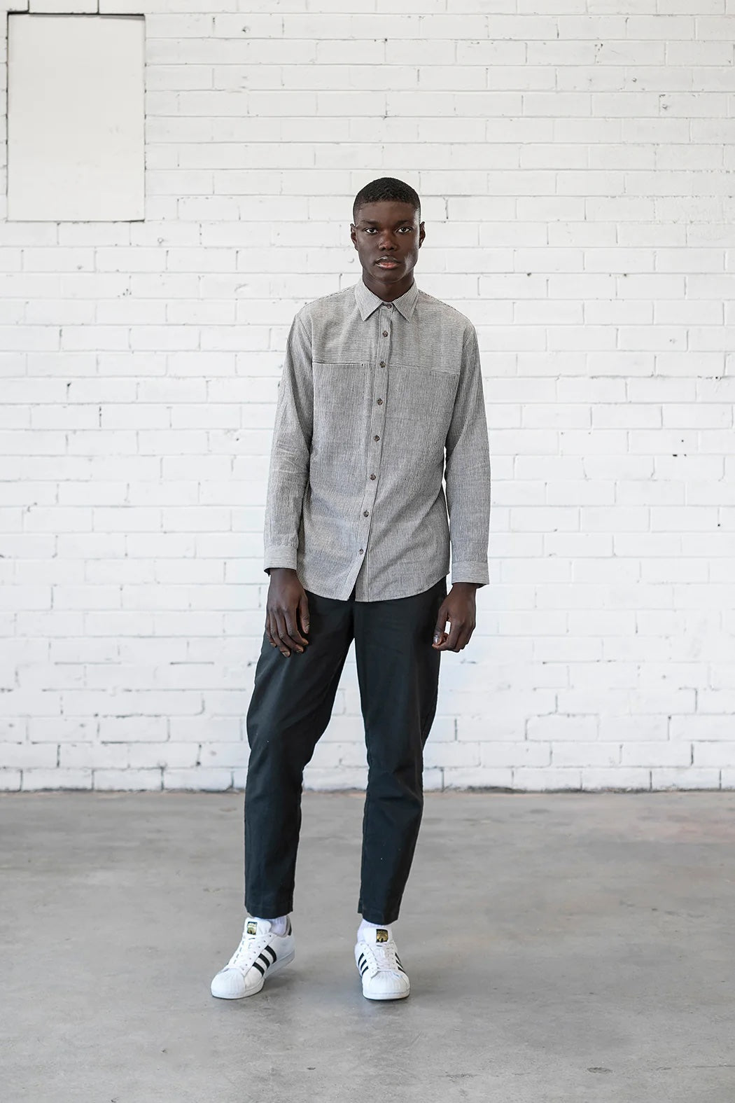 Man wearing the Men's Sanders Button Up sewing pattern from Elbe Textiles on The Fold Line. A shirt pattern made in soft cotton shirting, washed linen, woven hemp blends, lightweight denim, or flannelette fabric, featuring a semi-fitted shape, collar, front yoke with in-seam pockets, button front, and long sleeves with cuffs.