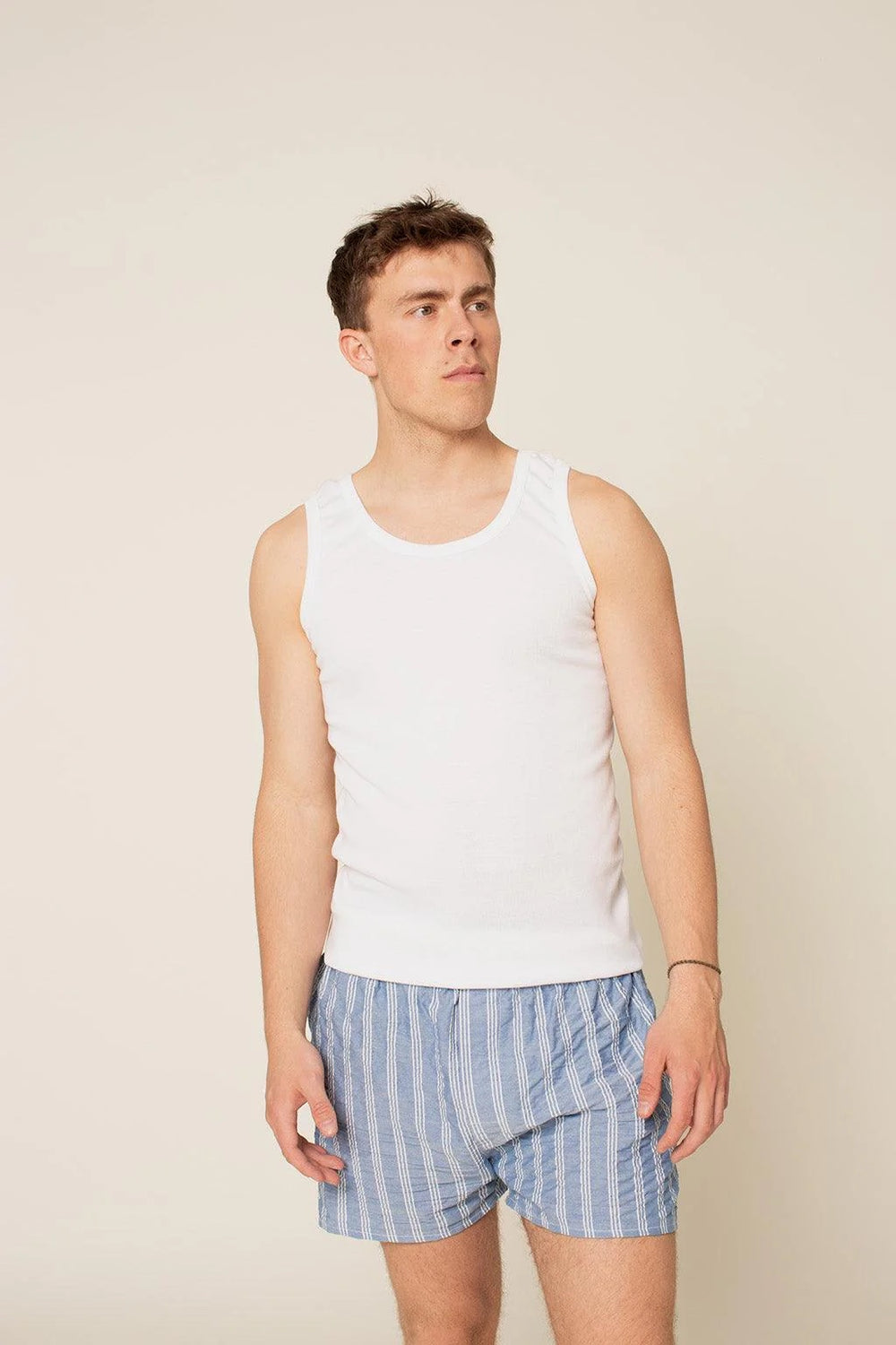 Man wearing the Men's Tank Top sewing pattern from Wardrobe by Me on The Fold Line. A fitted tank top pattern made in jersey or rib fabric, featuring binding at the neckline and armholes.