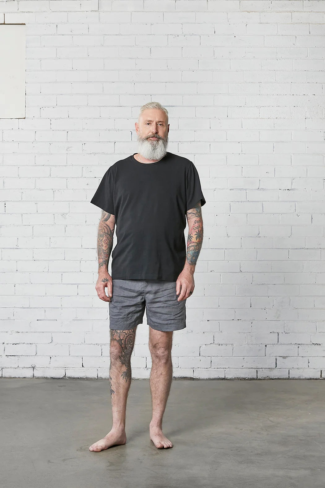 Man wearing the Men's Trigg Shorts sewing pattern from Elbe Textiles on The Fold Line. A shorts pattern made in tencel, chambray cotton, denim, linen, or boardshort fabric, featuring an elasticated waistband with a drawstring, side pockets, and back patch pockets.