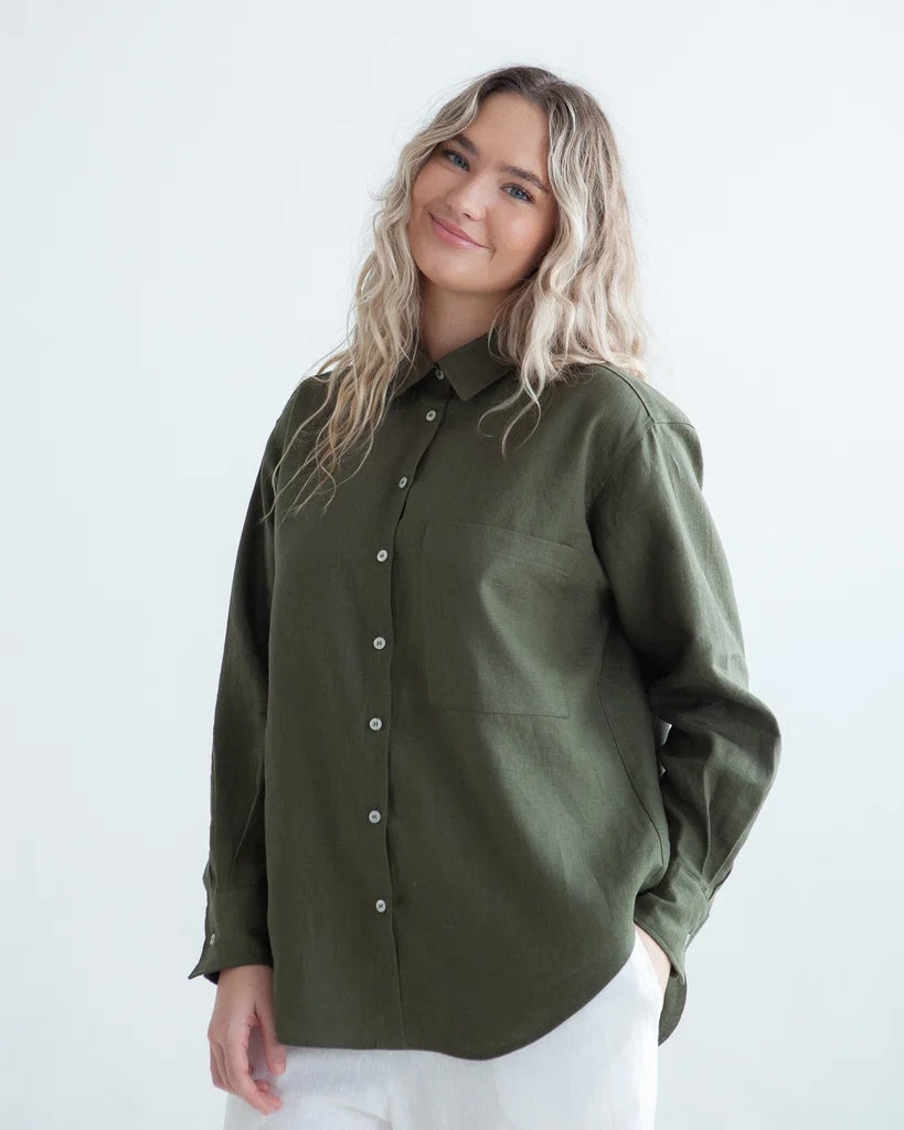 Woman wearing the Merritt Shirt sewing pattern from True Bias on The Fold Line. A shirt pattern made in shirting, cotton, linen, corduroy, or chambray fabric, featuring an oversized silhouette, collar and collar stand, button front, dropped shoulder, long sleeve with a sleeve placket and cuff, and patch chest pocket.