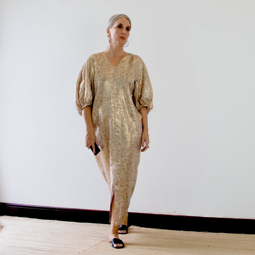 Woman wearing the Mersis Dress sewing pattern from Pattern Fantastique on The Fold Line. A dress pattern made in soft cotton, poplin, drapey linen, silk twill, rayon, or tencel fabric, featuring front and back V-necklines, voluminous elbow length sleeves, a front split, and maxi length.