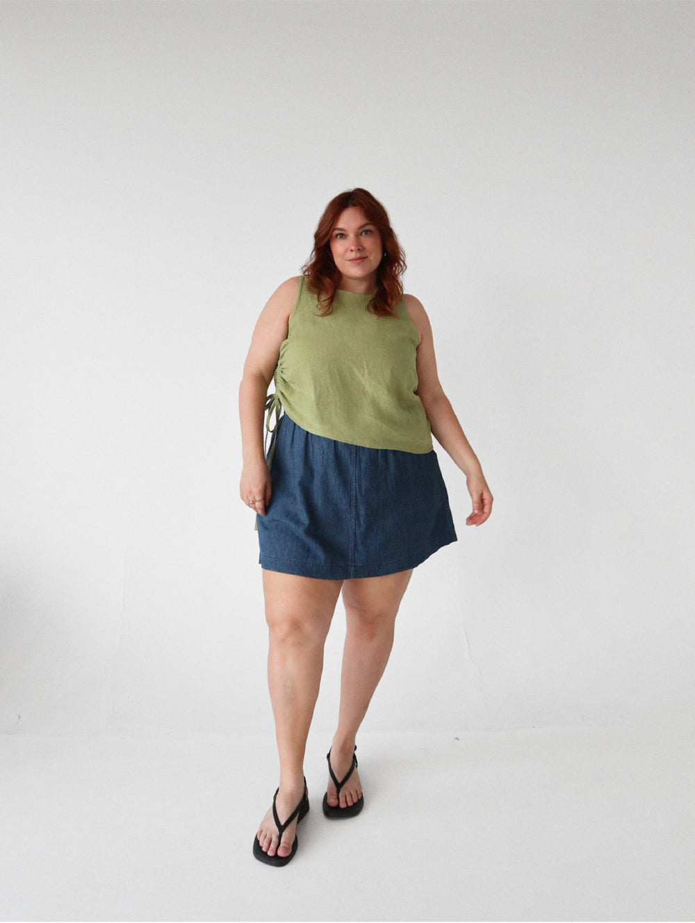 Woman wearing the Mesa Top sewing pattern from Les Perlines on The Fold Line. A sleeveless top pattern made in cotton, linen, rayon, viscose, or tencel twill fabric, featuring an adjustable side drawstring that creates soft gathers and an asymmetrical silhouette.