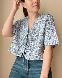 Woman wearing the Mette Top sewing pattern from Me & Kiddo Patterns on The Fold Line. A top pattern made in cotton, linen, or rayon fabric, featuring a boxy fit, V-neck, tie front, short sleeves, and cropped length.