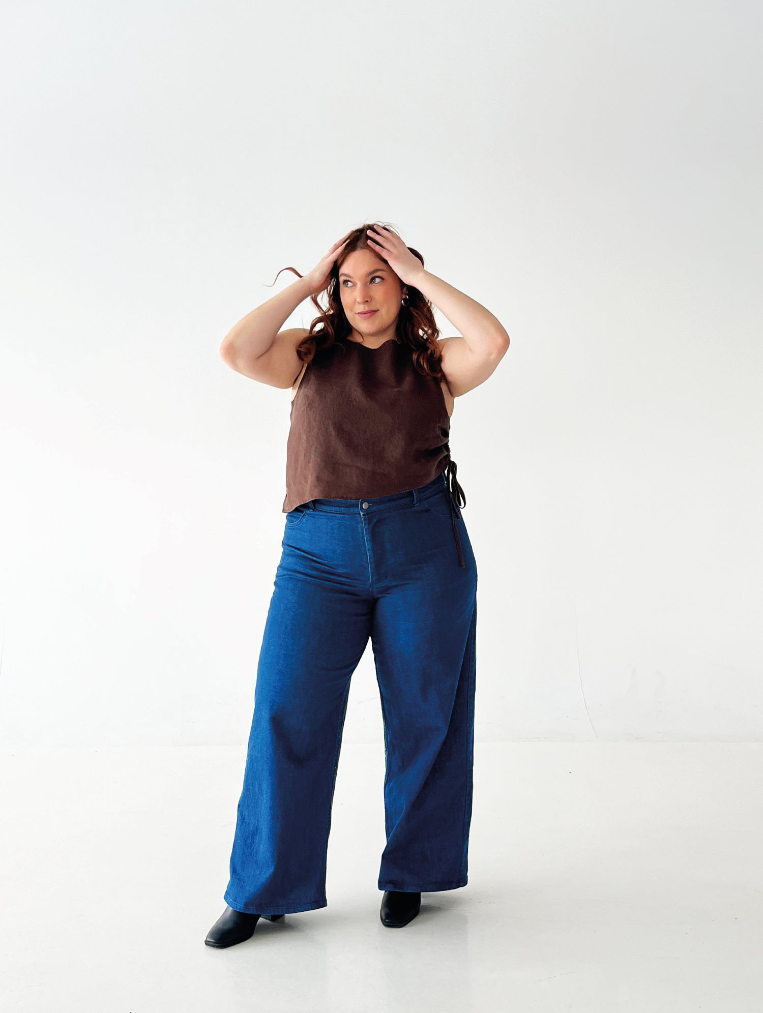 Woman wearing the Midtown Jeans sewing pattern from Les Perlines on The Fold Line. A trousers pattern made in stretch denim or corduroy fabric, featuring a high waist, zipper fly, front pockets, back yoke and patch pockets, and wide leg silhouette.
