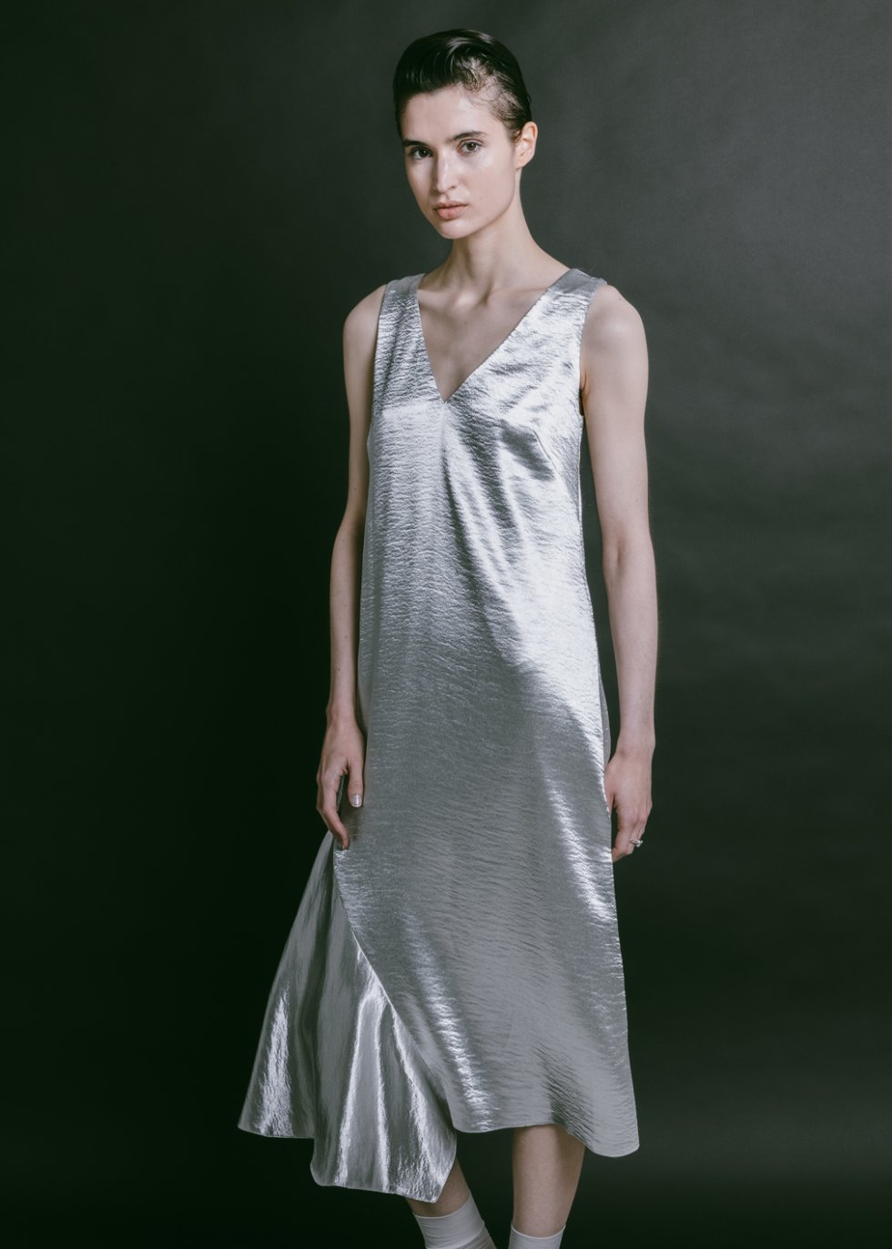 Woman wearing the Mildred Dress sewing pattern from Fibre Mood on The Fold Line. A 1920s-inspired sleeveless dress pattern made in satin, crepe, viscose, soft wool, or sequin fabric, featuring a straight cut, V-neckline, bust darts, and bias cut insert.