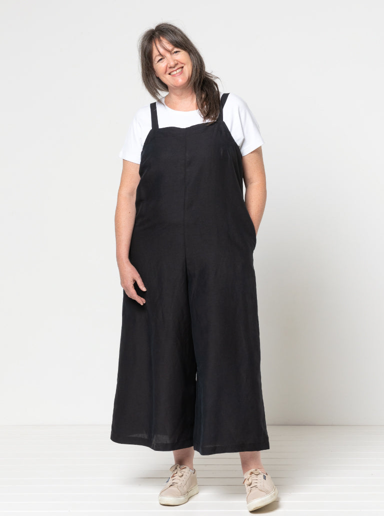 Woman wearing the Mildred Jumpsuit sewing pattern from Style Arc on The Fold Line. A jumpsuit pattern made in linen, cord, drill, crepe, or denim fabric, featuring shoulder straps, 7/8-length wide legs, and in-seam pockets.