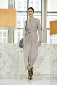 Woman wearing the Milena Dress sewing pattern from Fibre Mood on The Fold Line. A dress pattern made in viscose crepe, lyocell, cupro, poplin, chambray, fine corduroy, or lightweight denim fabric, featuring a button front, front twist, long sleeves, and elasticated back waist.