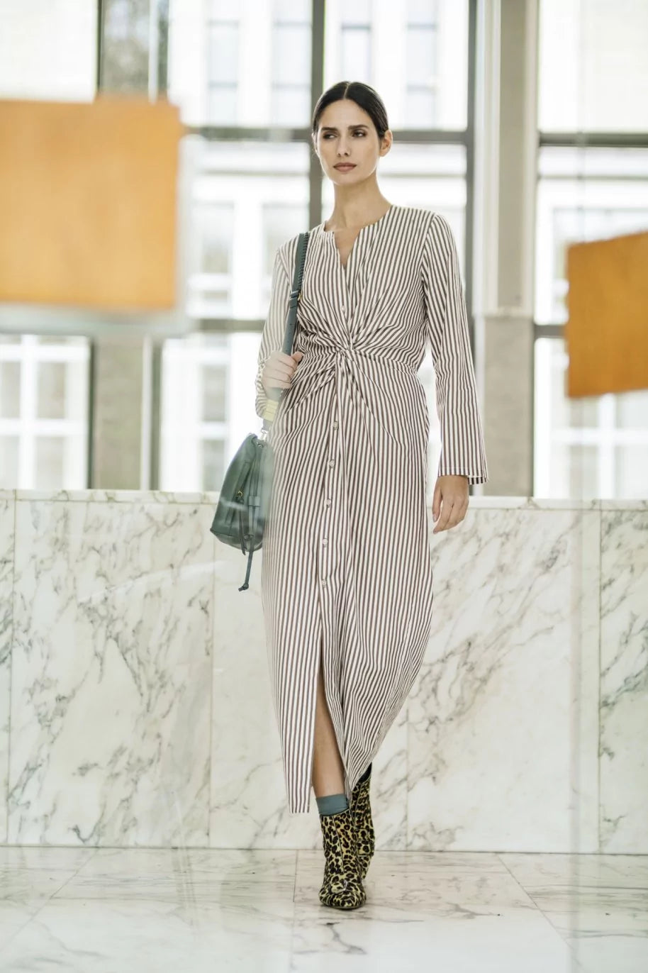 Woman wearing the Milena Dress sewing pattern from Fibre Mood on The Fold Line. A dress pattern made in viscose crepe, lyocell, cupro, poplin, chambray, fine corduroy, or lightweight denim fabric, featuring a button front, front twist, long sleeves, and elasticated back waist.