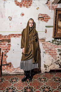 Woman wearing the Mingus Coat sewing pattern from Fibre Mood on The Fold Line. A coat pattern made in wool, wool blend, or coating fabric, featuring an integrated scarf, tie belt, and detachable sleeves.