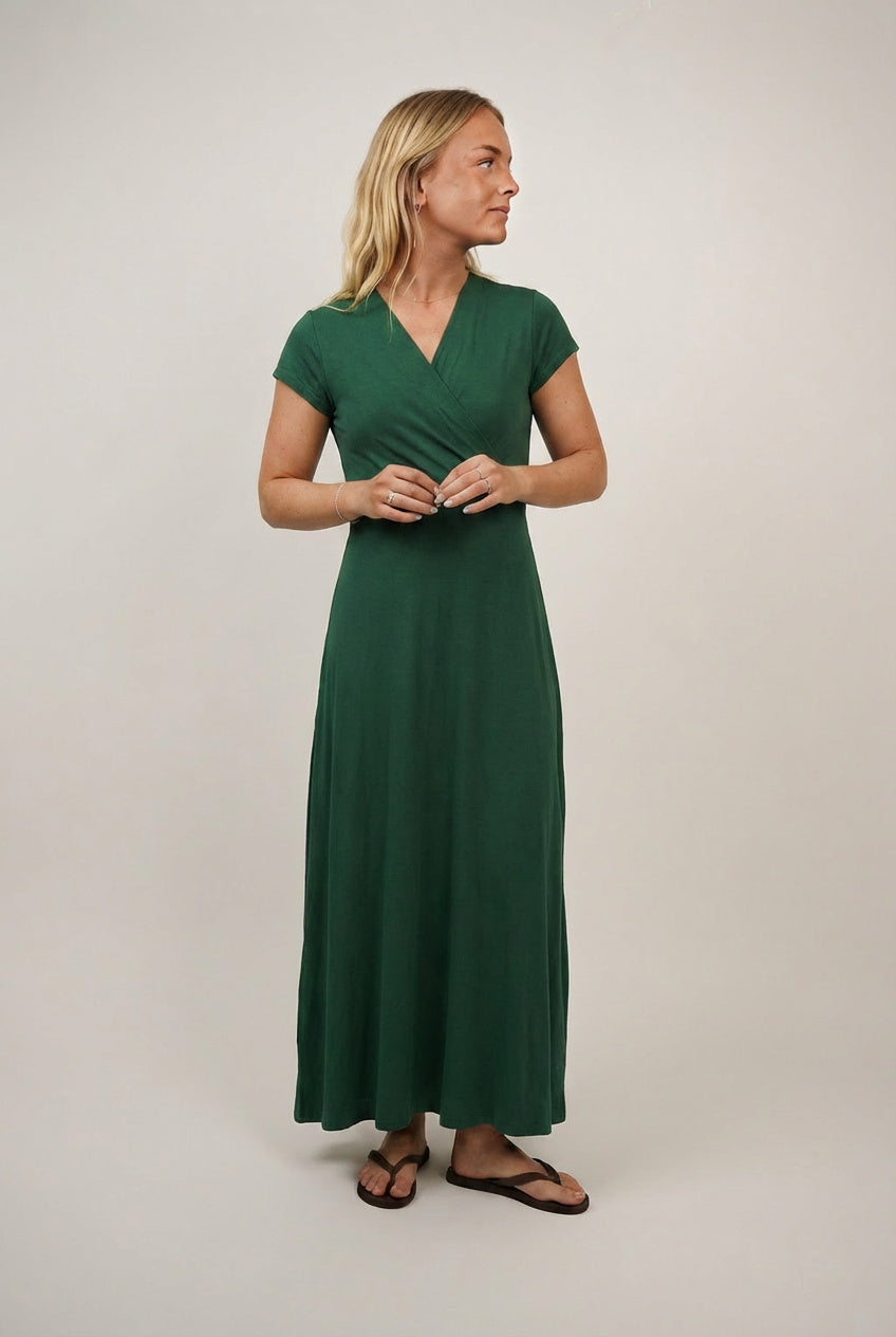 Woman wearing the Mirri Dress sewing pattern from Wardrobe by Me on The Fold Line. A dress pattern made in jersey fabric, featuring a faux wrap front, V-neckline, short grown-on sleeves, and maxi length.