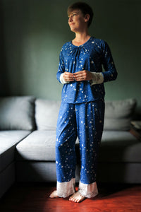 Woman wearing the Mona Sira Pajamas sewing pattern from Primrose Dawn on The Fold Line. A nightwear pattern made in knit fabric for the top and knit or linen, rayon challis, crinkle gauze, cotton lawn, or satin fabric for the trousers, featuring a top with a round neckline, neckline gathers, and long raglan sleeves with lace cuffs, and elastic waist trousers with lace cuffs.