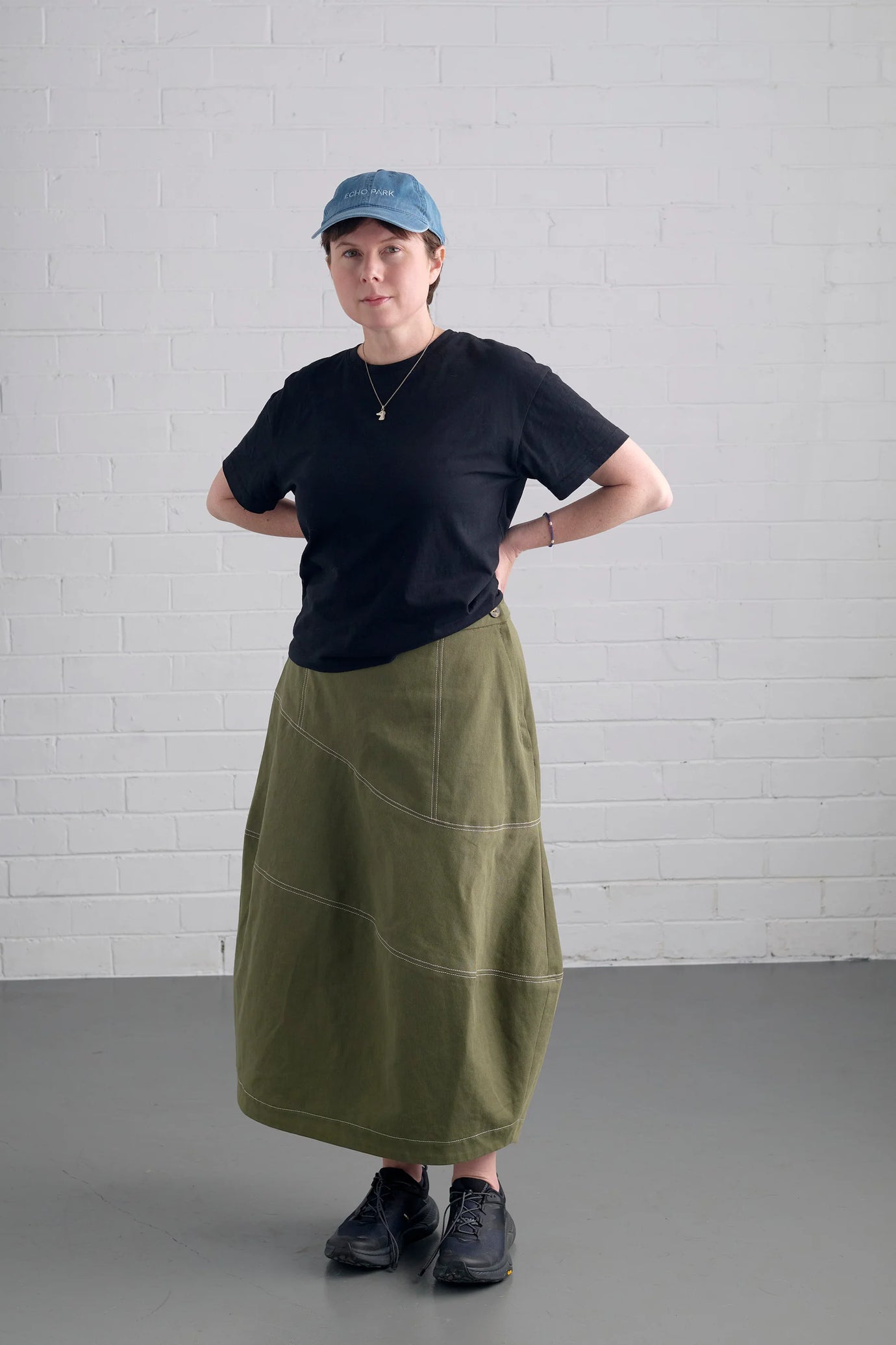 Woman wearing the Mornington Skirt sewing pattern from In the Folds on The Fold Line. A skirt pattern made in linen, linen blends, cotton drill or twill, denim, wool, midweight silk, or tencel twill fabric, featuring an asymmetrical lantern silhouette, lapped side zip, topstitching, and ankle length.