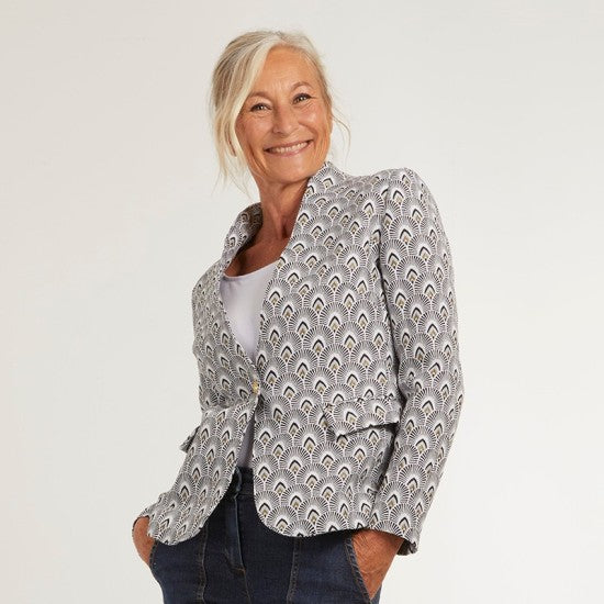Woman wearing the Naïma Jacket sewing pattern from Coralie Bijasson on The Fold Line. A blazer pattern made in cotton satin, cotton piqué, denim, wool, gabardine, or jacquard fabric, featuring a stand-up shawl collar, one button closure, and flap pockets. 