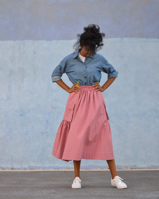 Woman wearing the Neu Skirt sewing pattern from Pauline Alice on The Fold Line. A skirt pattern made in poplin, viscose, nylon, gabardine, or technical fabric, featuring a drawstring cord in front, an elastic waistband in back, and cargo pockets with bellows and flaps.