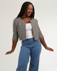 Woman wearing the Nicole Jacket sewing pattern from Coralie Bijasson on The Fold Line. A bolero pattern made in cotton satin, cotton piqué, wool, wild silk, or jacquard fabric, featuring a round neckline, 3/4 sleeves, and a cropped hemline.