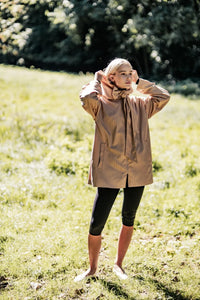 Woman wearing the Nigel Jacket sewing pattern from Fibre Mood on The Fold Line. A jacket pattern made in gabardine, twill, canvas, wool, wool blend, or technical fabric, featuring a relaxed fit, hood that extends into ties, front zip, and pockets.
