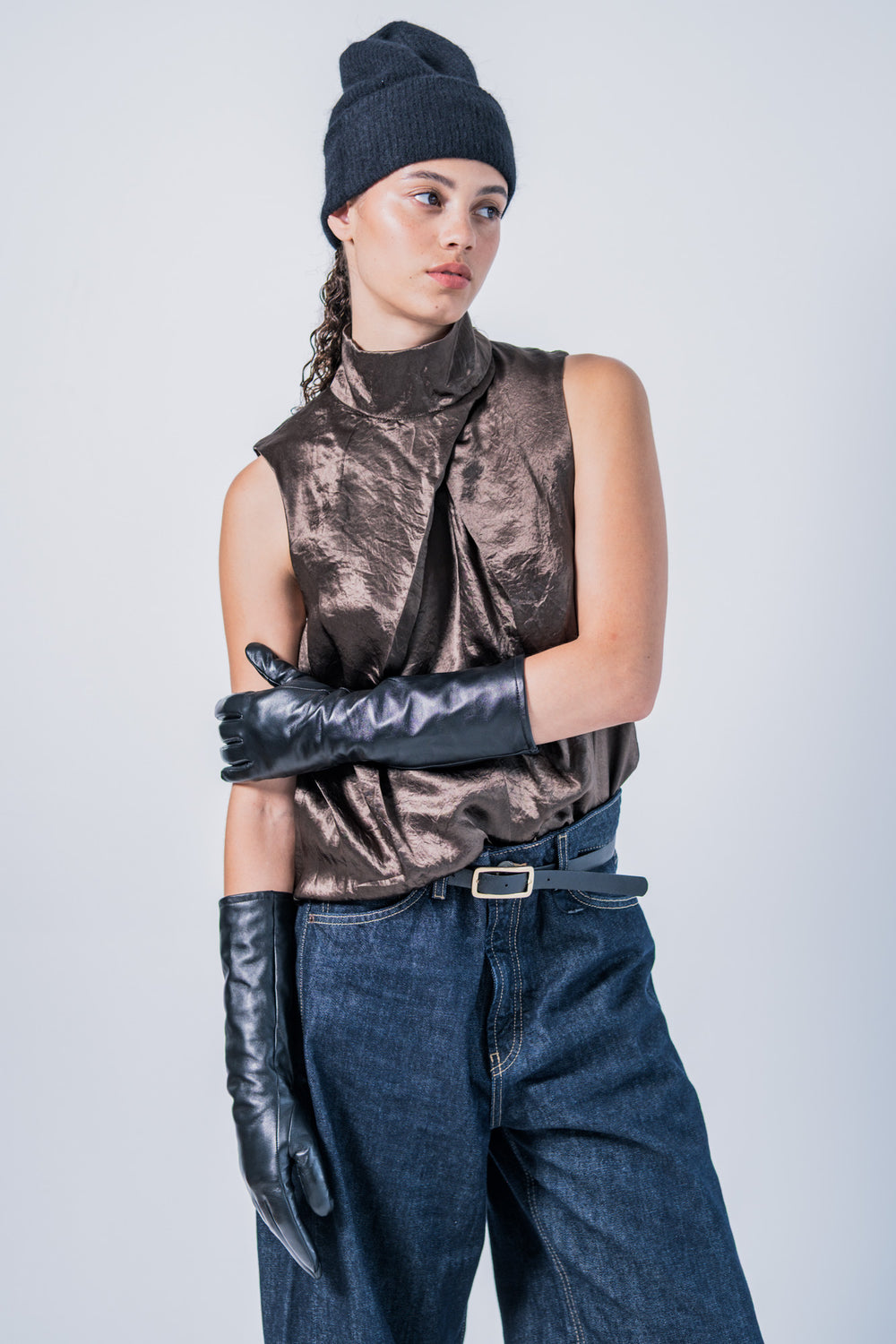 Woman wearing the Niva Top sewing pattern from Fibre Mood on The Fold Line. A sleeveless top pattern made in poplin, viscose, leather, wool, or silk fabric, featuring a high stand-up collar, front pleats, and back zip.