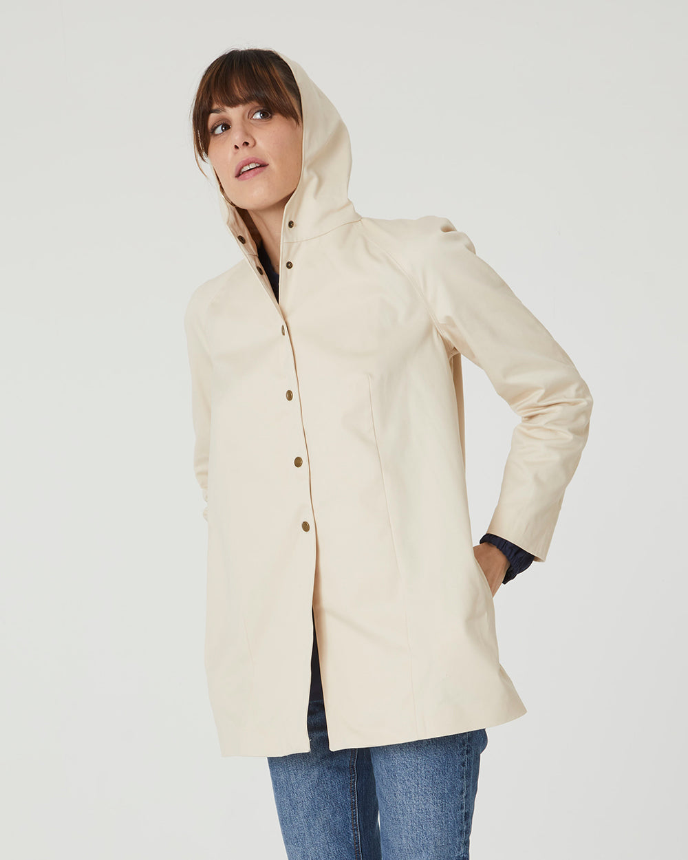 Woman wearing the Nora Coat sewing pattern from Coralie Bijasson on The Fold Line. A jacket pattern made in wool, softshell, or coated canvas fabric, featuring a snap button front, raglan sleeves, and hood.