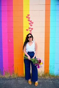 Woman wearing the Nora Tank sewing pattern from Sew Bake Make on The Fold Line. A sleeveless top pattern made in linen, linen blend, cotton voile, or cotton blend fabric, featuring a boxy fit, deep V-neck, and ties at the shoulders.