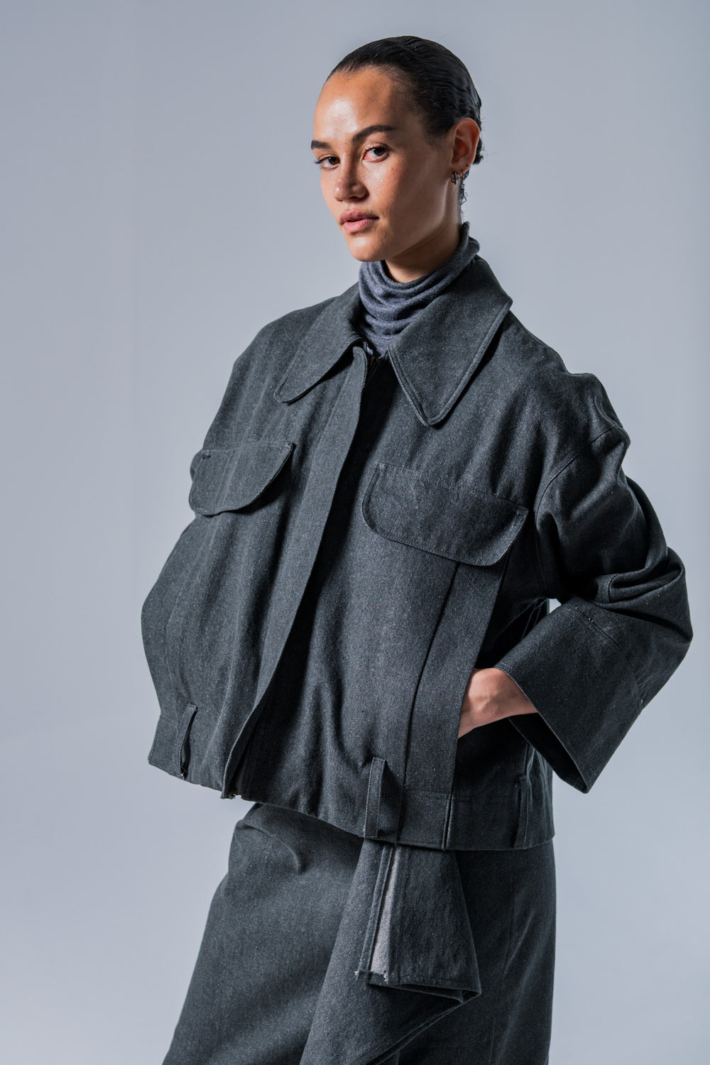 Woman wearing the Nori Jacket sewing pattern from Fibre Mood on The Fold Line. A workwear style jacket pattern made in denim, corduroy, velvet, cotton twill, woven jacquard, or leather fabric, featuring an oversized collar, front zip, welt pockets with decorative flaps, and topstitching.