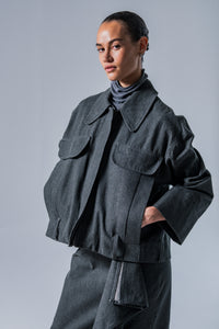 Woman wearing the Nori Jacket sewing pattern from Fibre Mood on The Fold Line. A workwear style jacket pattern made in denim, corduroy, velvet, cotton twill, woven jacquard, or leather fabric, featuring an oversized collar, front zip, welt pockets with decorative flaps, and topstitching.