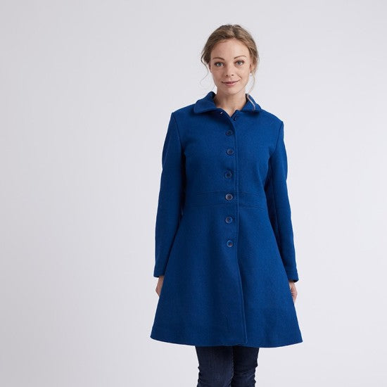 Woman wearing the Nuage Coat sewing pattern from Coralie Bijasson on The Fold Line. A coat pattern made in wool, jacquard, or denim fabric, featuring a rounded point collar, button front, defined waist, side seam pockets, and A-line silhouette.