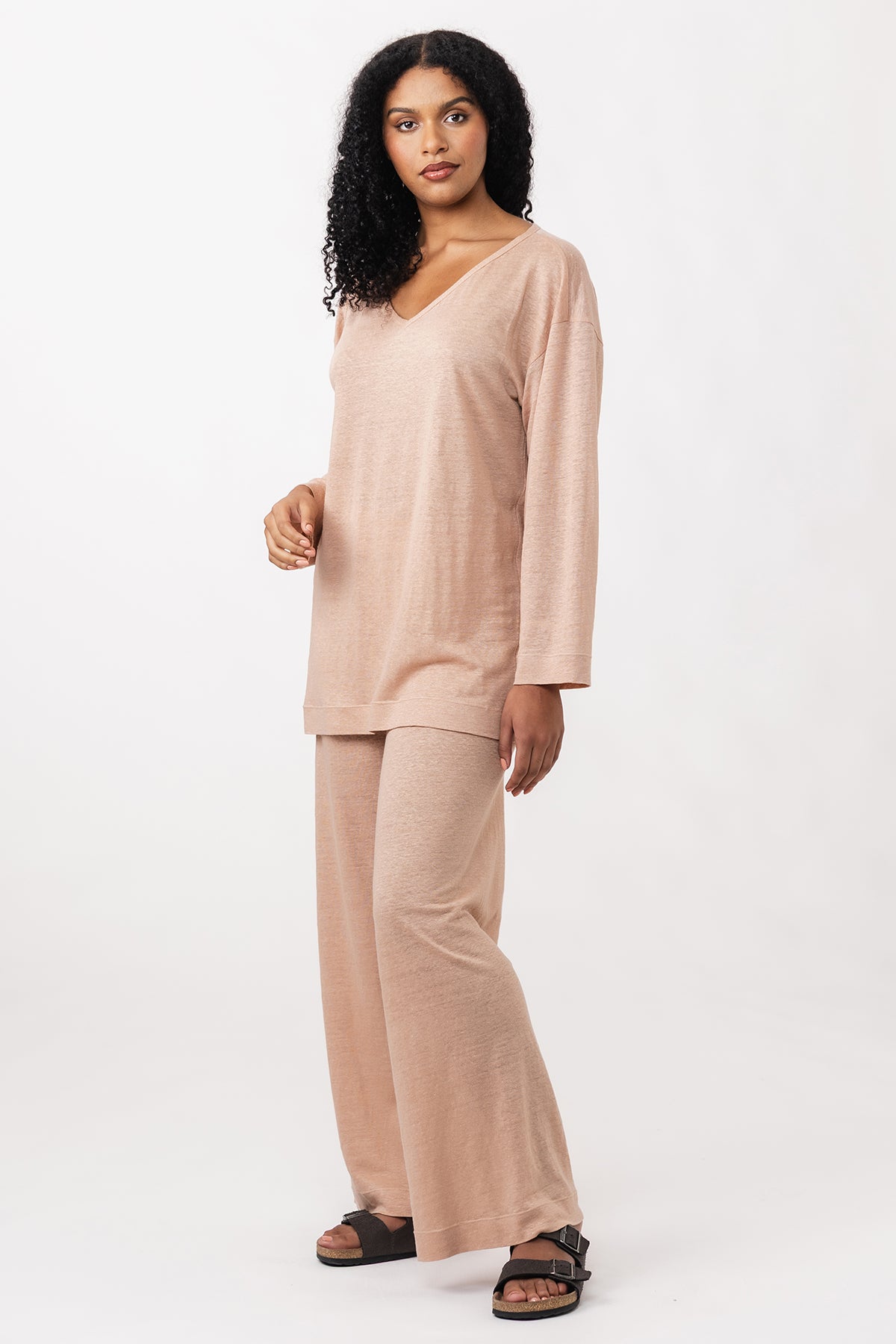 Woman wearing the Olo Tee and Pants sewing patterns from Named on The Fold Line. Top and pants patterns made in knit fabric, featuring a relaxed fit, deep V-neck tee with long sleeves, and wide leg pants with a high elasticated waist and no side seams.
