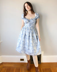 Woman wearing the Ophelia Dress sewing pattern from Oh Me Oh My Sewing on The Fold Line. A dress pattern made in quilting cotton, washed linen, viscose, cotton lawn, voile, or rayon challis fabric, featuring a corset inspired bodice with a sweetheart neckline and drawstring detail, short puff sleeves, and a gathered skirt.