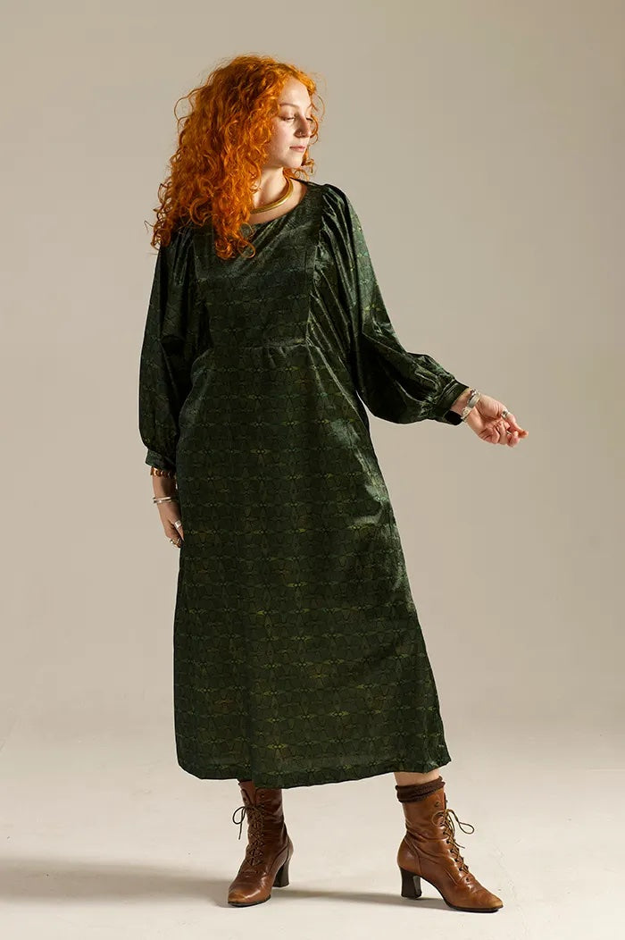 Woman wearing the Otus Frock sewing pattern from Sew Different on The Fold Line. A dress pattern made in cotton, viscose, linen, cupro, lightweight denim, or needlecord fabric, featuring a round neckline, bib at the front and back, long batwing sleeves, and midi length.
