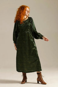 Woman wearing the Otus Frock sewing pattern from Sew Different on The Fold Line. A dress pattern made in cotton, viscose, linen, cupro, lightweight denim, or needlecord fabric, featuring a round neckline, bib at the front and back, long batwing sleeves, and midi length.