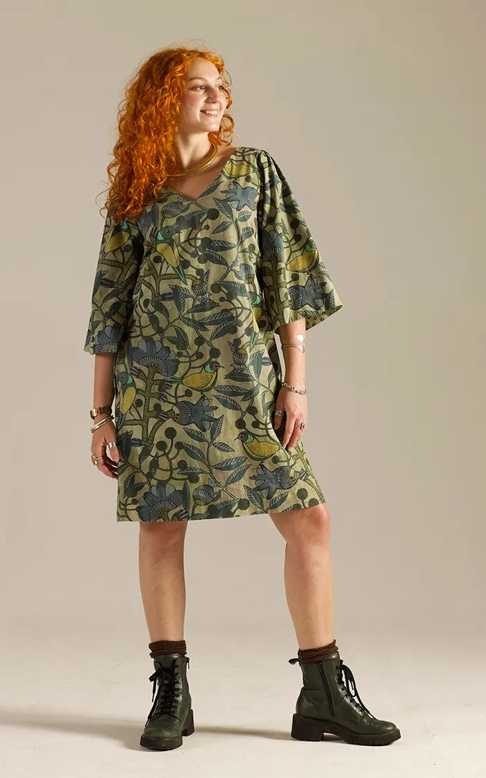 Woman wearing the Paradise Dress sewing pattern from Sew Different on The Fold Line. A shift dress pattern made in cotton, linen, viscose, velvet, denim, needlecord, wool, or medium or heavy weight jersey fabric, featuring a relaxed fit, A-line silhouette, V-neckline, French darts, flared sleeves, pockets, and knee length.