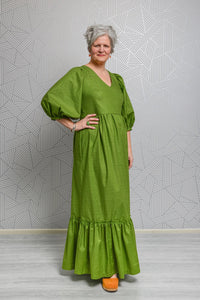 Woman wearing the Penelope Dress sewing pattern from Emporia Patterns on The Fold Line. A dress pattern made in cotton poplin or lawn, viscose lawn, linen, chambray, broderie anglaise, needlecord, crepe, or jacquard fabric, featuring a V-neck, puff  sleeves, and maxi length gathered skirt with pockets and a hem frill.