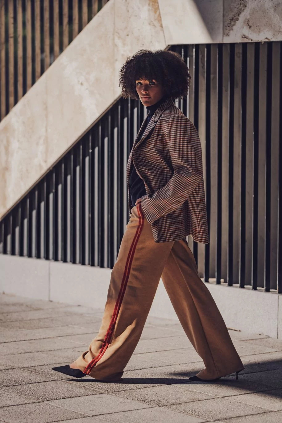 Woman wearing the Perry Trousers sewing pattern from Fibre Mood on The Fold Line. A trousers pattern made in poplin, corduroy, gabardine, cotton twill, viscose crepe, linen, modal, or nylon fabric, featuring an elastic waistband with an optional drawstring, side seam pockets, and decorative side stripes.