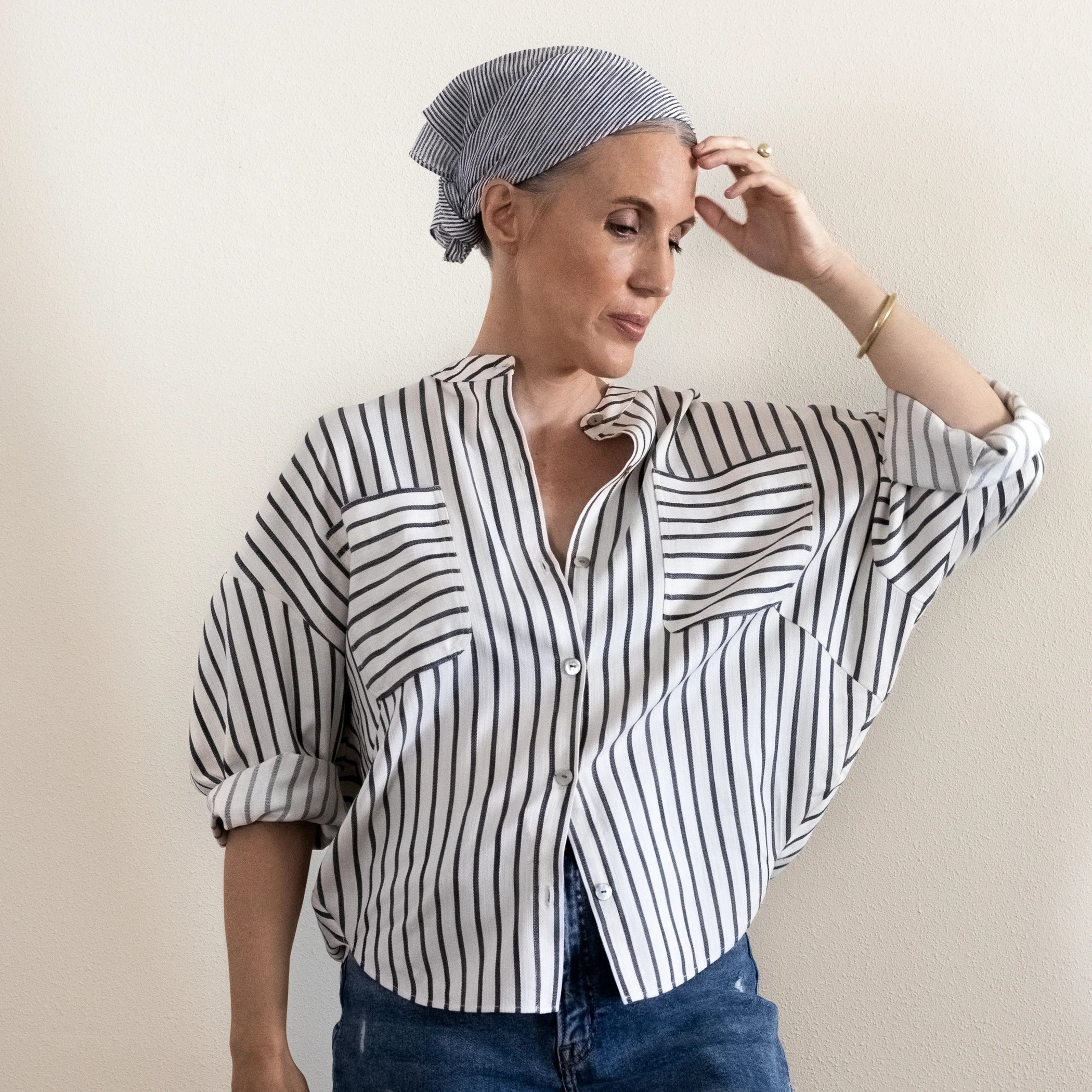 Woman wearing the Phen Shirt sewing pattern from Pattern Fantastique on The Fold Line. A shirt pattern made in silk, cotton shirting, cotton poplin, linen, or denim fabric, featuring a button front, batwing sleeves, pockets, and shaped hemline.