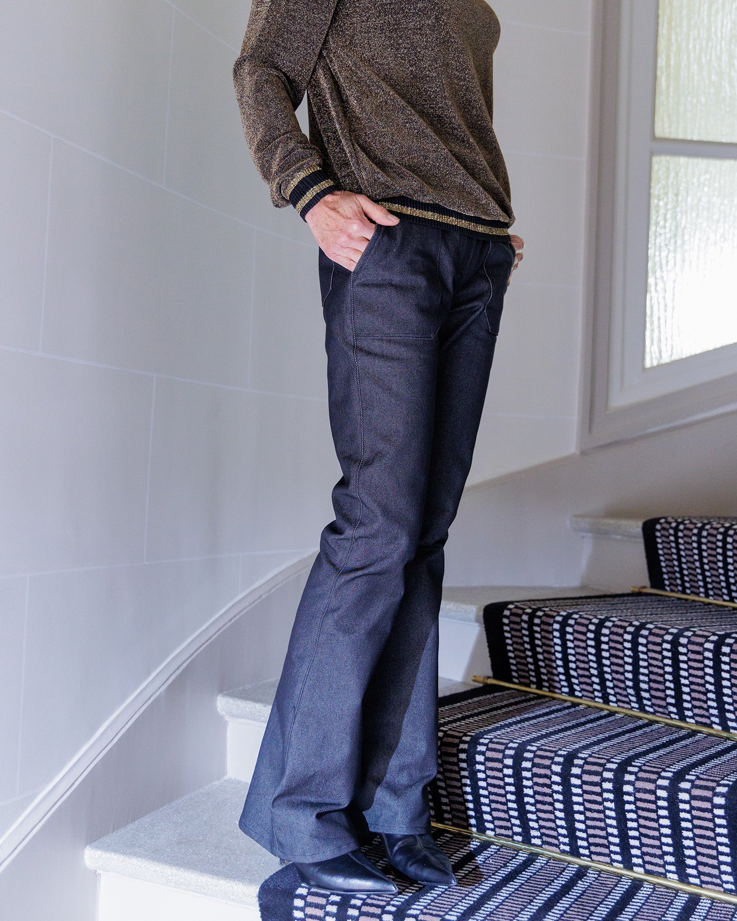 Woman wearing the Philippine Pants sewing pattern from Coralie Bijasson on The Fold Line. A pants pattern made in stretch denim, corduroy, or cotton fabric, featuring a high waist, jeans-style back yoke, fly front, patch pockets, and retro flared leg.