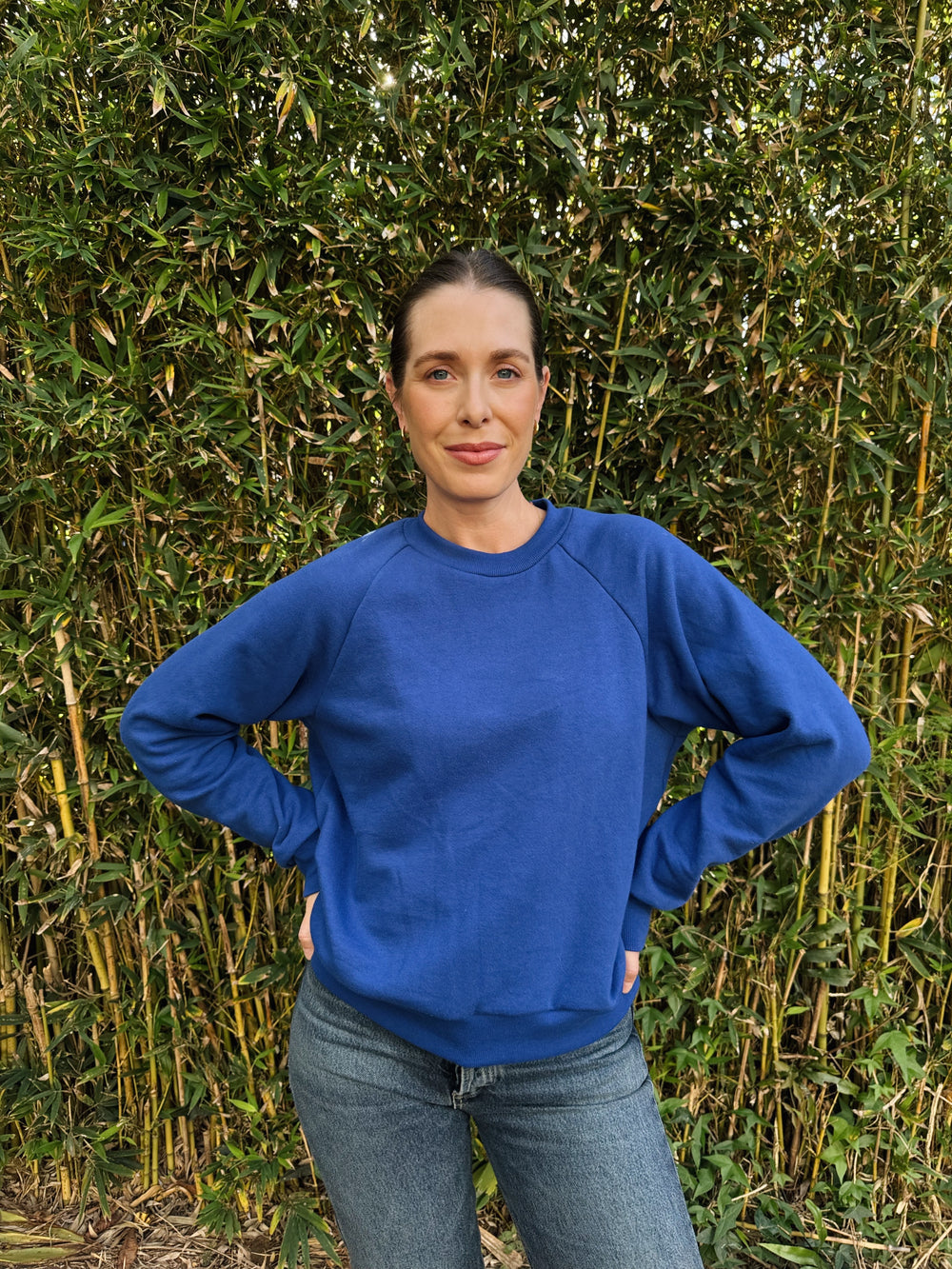 Woman wearing the Pine Raglan Sweatshirt sewing pattern from Paradise Patterns on The Fold Line. A sweatshirt pattern made in French terry, fleece, waffle knit, or heavy weight jersey fabric, featuring a slightly oversized fit, round neckline, and long sleeves.